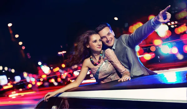Elegantes Paar, das nachts mit einer Limousine unterwegs ist — Stockfoto