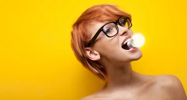 Молода жінка тримає лампочку в роті — стокове фото