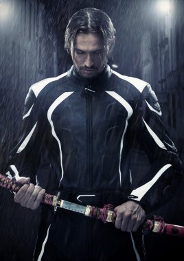 Muscular man holding samurai sword in on a rainy night clipart