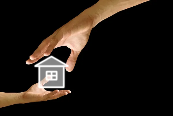 A mão grande dá o ícone de casa à mão pequena — Fotografia de Stock