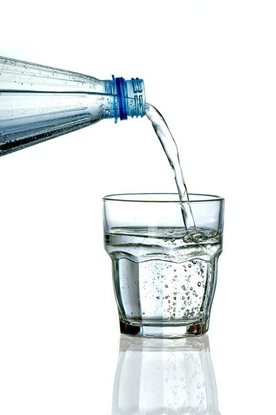 Наполнение стакана водой на белом фоне — стоковое фото