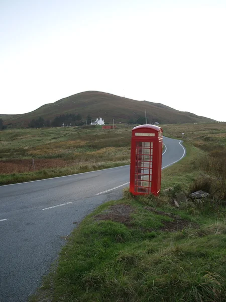 Stock image Lonely red phoneboot next to an empty road