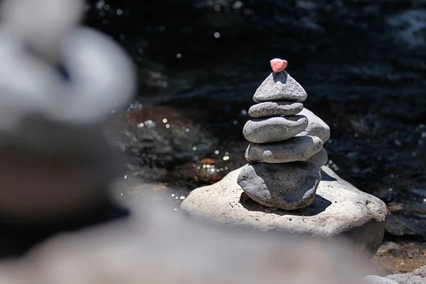 Cairn com pedra vermelha pelo riacho — Fotografia de Stock