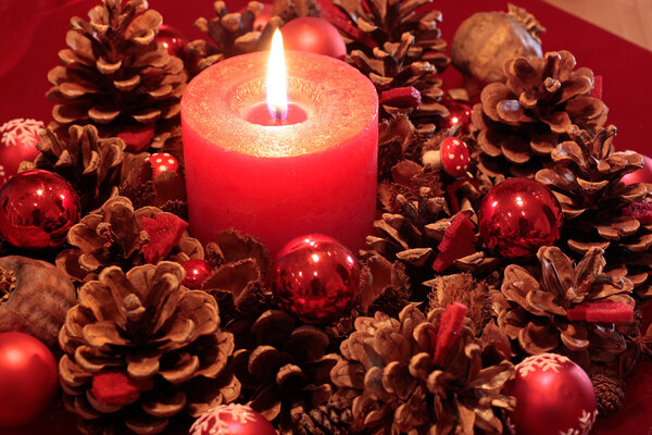 Advent wreath with pine cones and burning candle