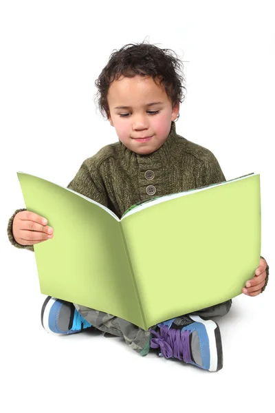 En liten gutt som leser en bok – stockfoto