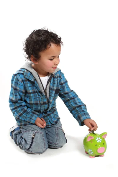 stock image Little boy putting money into a piggy bank