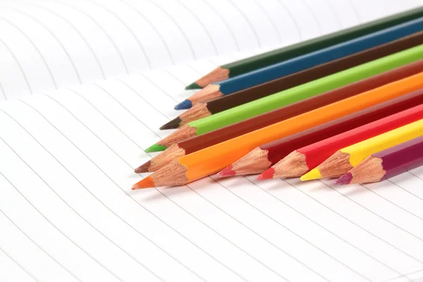 Pencil crayons on white writing paper — Stock Photo, Image