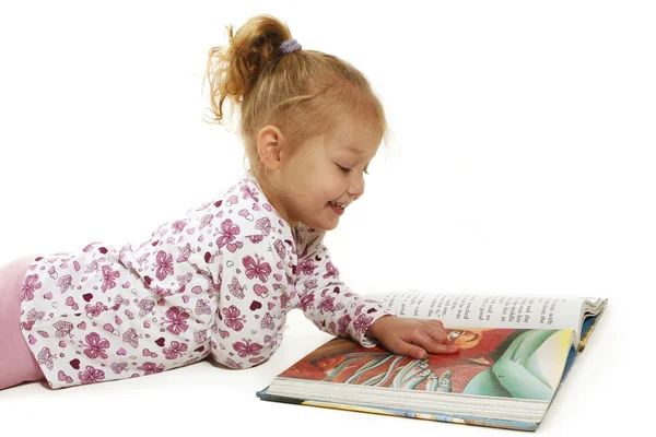 Liten jente leser i en bok – stockfoto