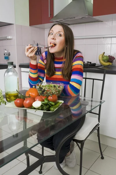 Kobieta jedząca sałatkę w kuchni — Zdjęcie stockowe