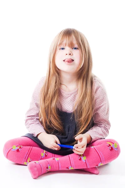 Little girl sit with stick her tongue out — Stock Photo, Image