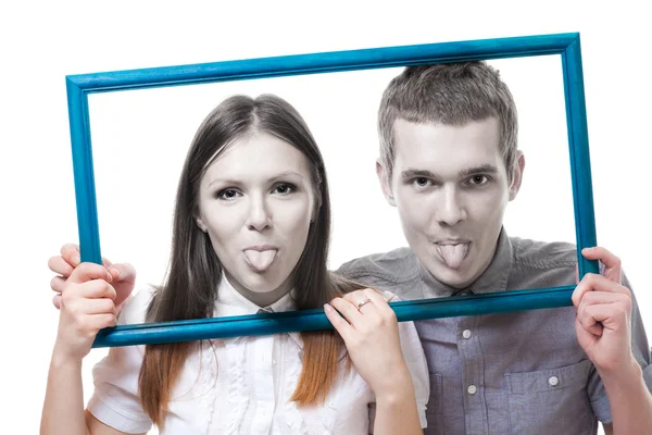 Couple look from frame with stick out tongue — Stock Photo, Image