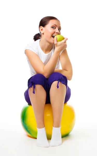 Молода жінка сидить на м'ячі з яблуком — стокове фото