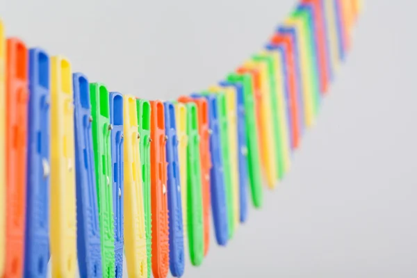 Many colorful clothe pegs in a row — Stock Photo, Image