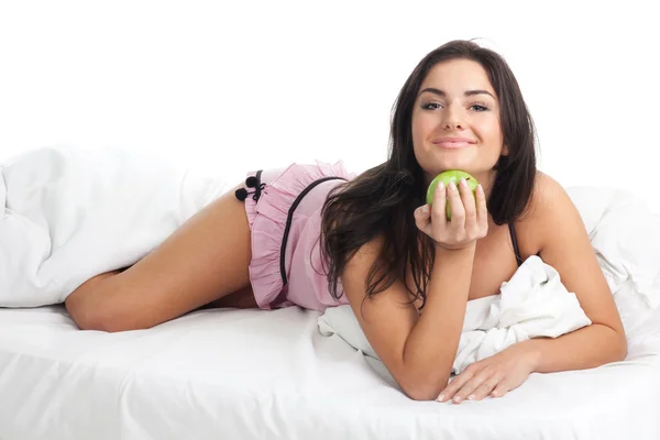 Ευτυχής νεαρή γυναίκα στο κρεβάτι με την apple — Φωτογραφία Αρχείου
