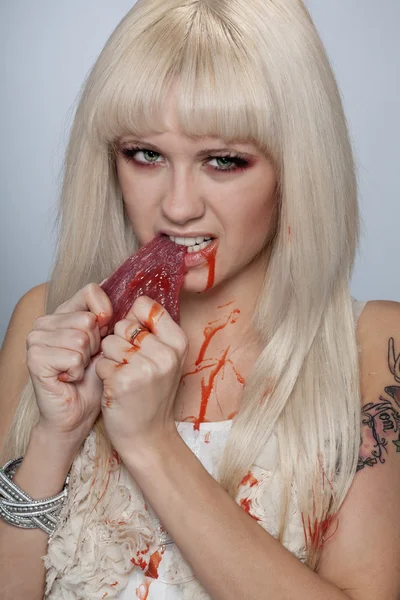 Menina rasgar carne crua com sangue — Fotografia de Stock