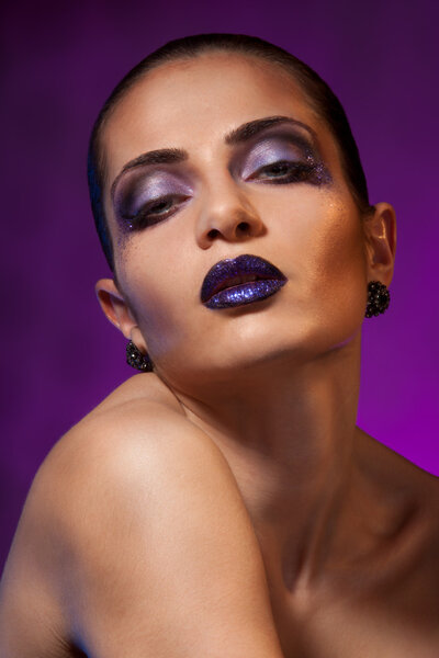 Beauty shoot of a woman with strong purple makeup and background