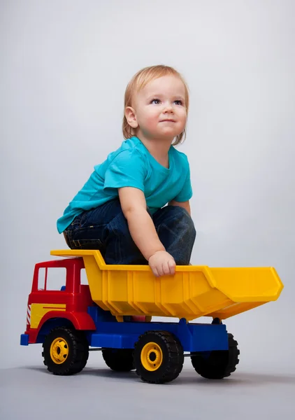 Парень сидит на игрушечном грузовике — стоковое фото