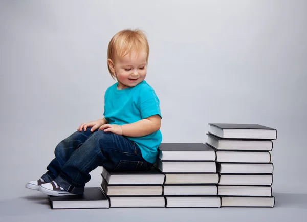 Kid sitting on a a steps made of books — Stock Photo, Image