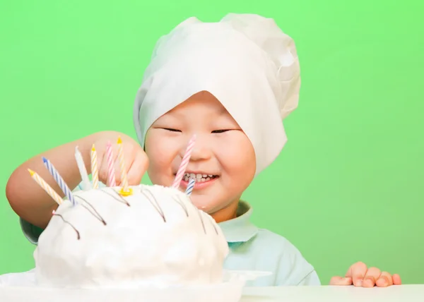 Boy putting candles in birthday cake — Stock Photo, Image