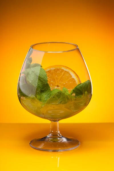 Glas met munt en oranje drankje — Stockfoto