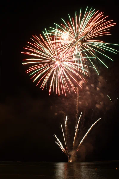 Daisy-like firework display reflecting in the water — Stock Photo, Image