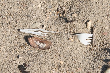 Broken plastic fork in the sand clipart