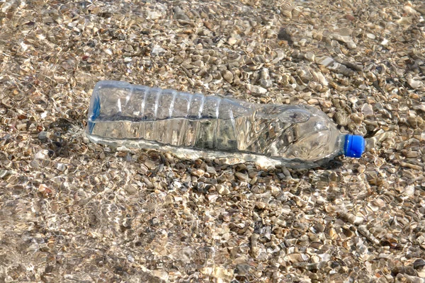 Bouteille en plastique dans l'eau de mer peu profonde — Photo
