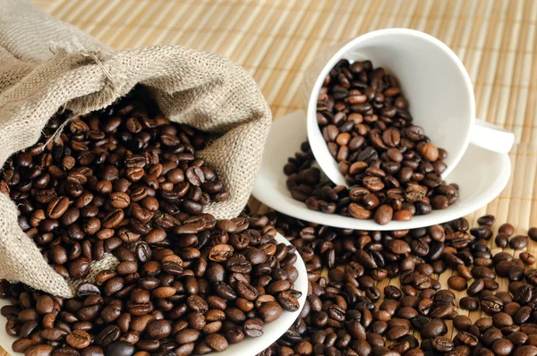 Granos de café con una taza blanca y saco —  Fotos de Stock