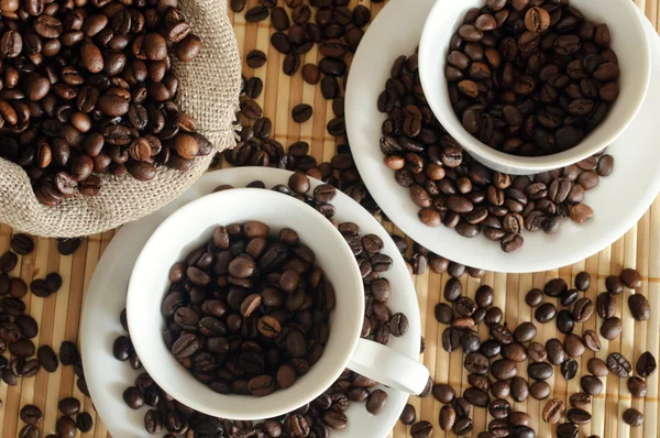 एक पांढरा कप आणि सॅक सह कॉफी बीन्स — स्टॉक फोटो, इमेज