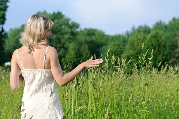 Žena dotýká trávy — Stock fotografie