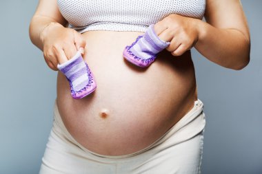 Pregnant woman holding pair of shoes clipart