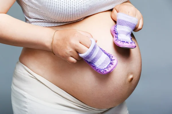 Mujer sosteniendo un par de zapatos para bebé —  Fotos de Stock