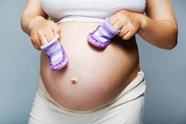 Mulher grávida segurando par de sapatos — Fotografia de Stock