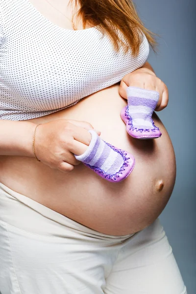Mujer sosteniendo un par de zapatos para bebé —  Fotos de Stock