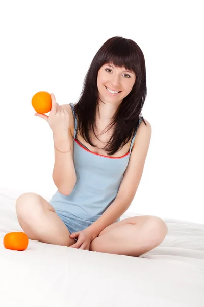Kobieta na łóżku trzymając pomarańczowe — Zdjęcie stockowe