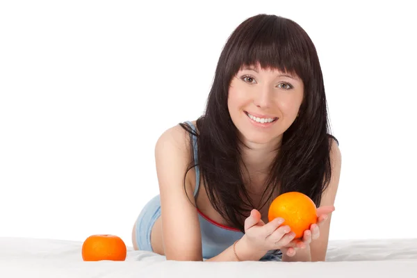 Женщина на кровати держит оранжевый — стоковое фото
