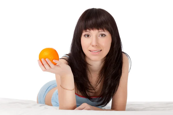 Vrouw op bed houden oranje — Stockfoto