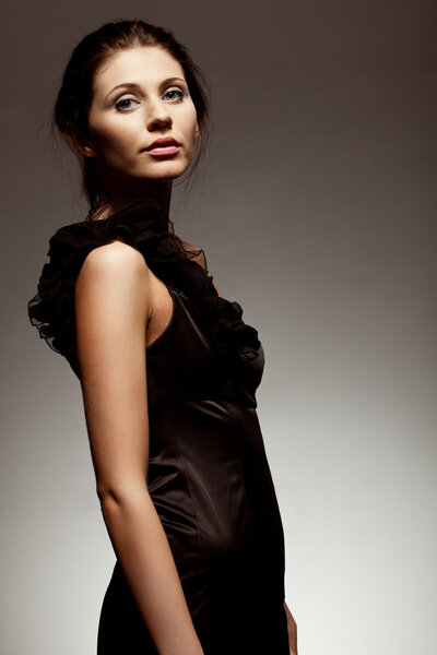 Woman wearing black dress, studio portrait over gradient background