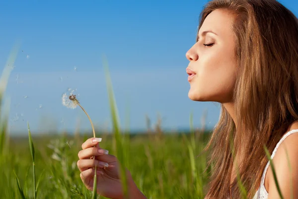 Woman blowing to dandelion — Stock Photo, Image