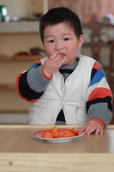 Čínský chlapec jíst ovoce — Stock fotografie