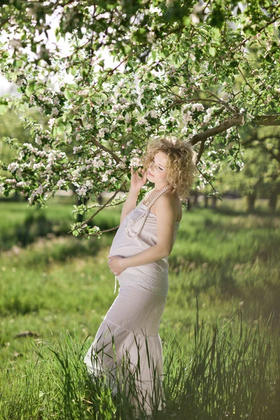 꽃피는 정원에 있는 아름다운 임신부 — 스톡 사진