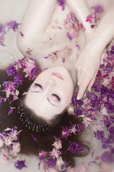 Atraktivní nahá dívka má lázně s mlékem a růží. lázeňské léčení — Stock fotografie