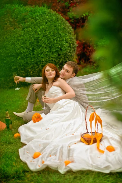 Blijde bruid en bruidegom op gras in park — Stockfoto