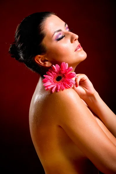 Attractive young woman with pink flower — Stock Photo, Image