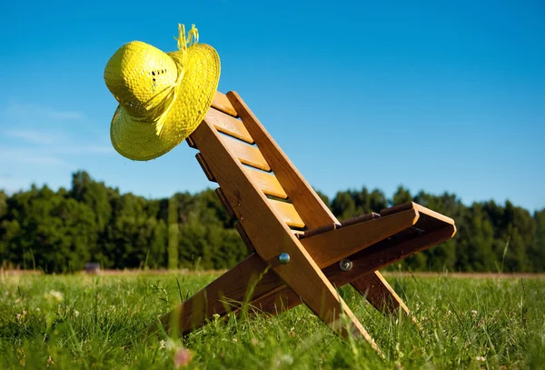 Armchair and straw hat outdoors — Stock Photo, Image