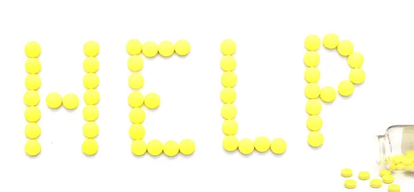 Żółte tabletki pisowni słowa pomagają na białym tle — Zdjęcie stockowe