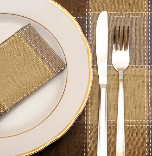 Kniv och gaffel med vit platta på träbord — Stockfoto