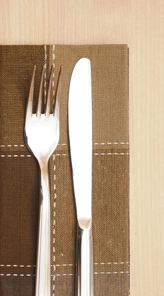 Knife and fork with napkin on wooden table — Stock Photo, Image