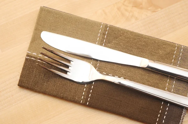 Knife and fork with napkin on wooden table — Stock Photo, Image