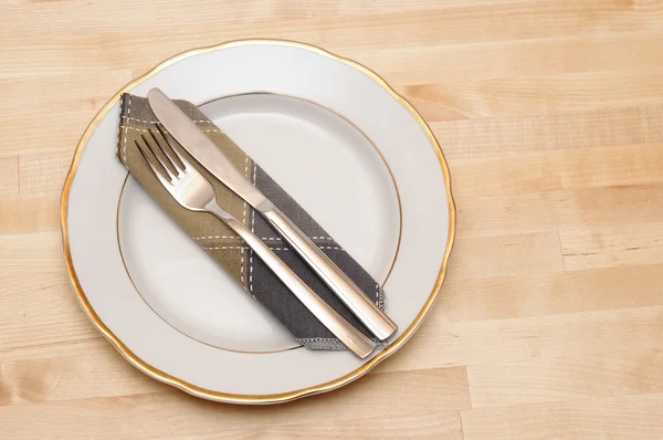 Cuchillo y tenedor con plato blanco sobre mesa de madera — Foto de Stock